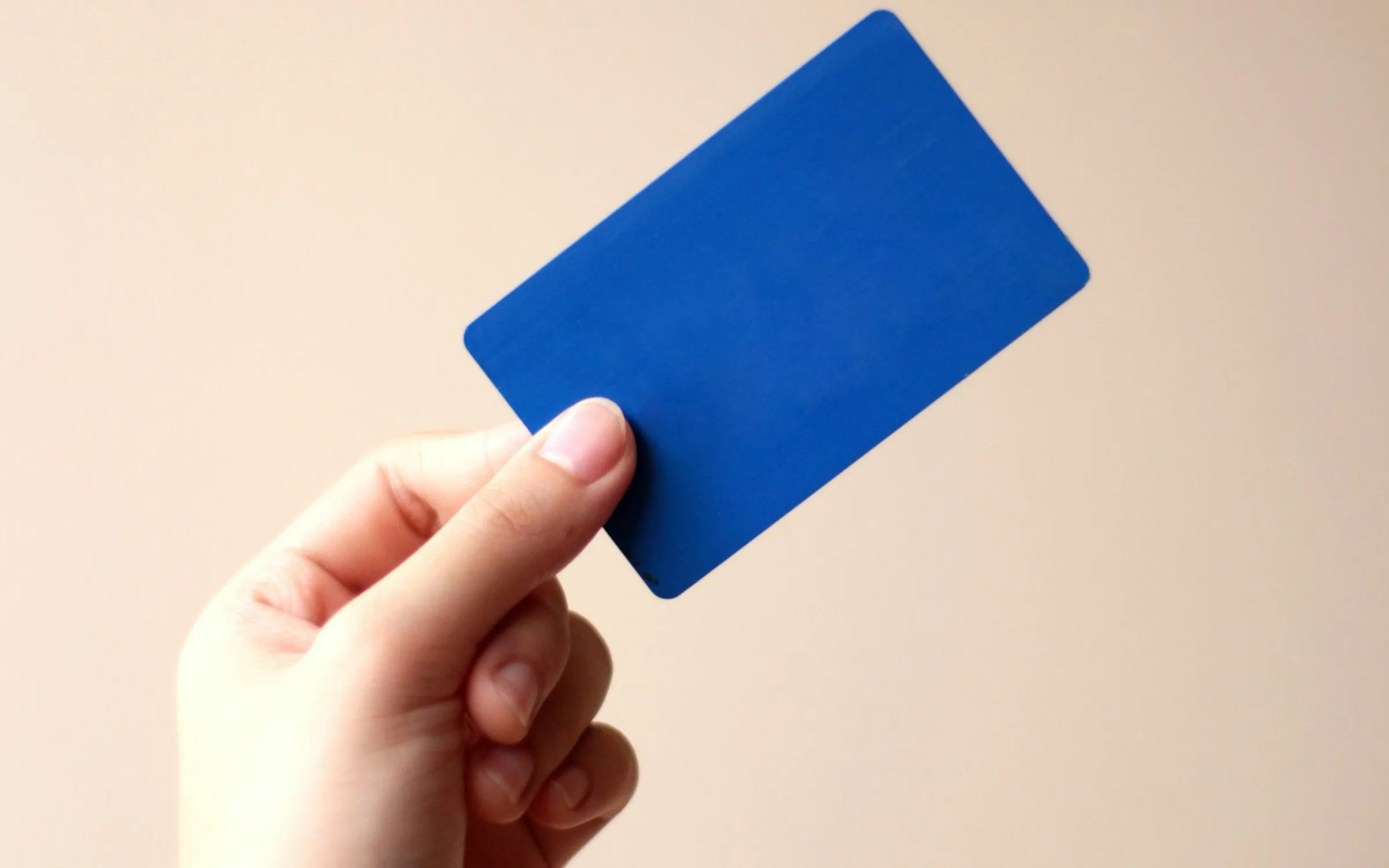 A hand holding up a blue payment card