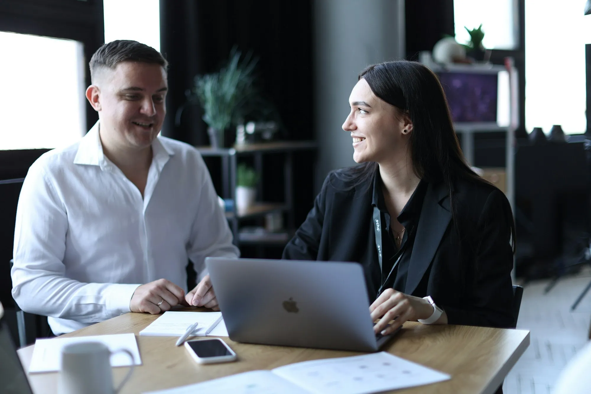 Two colleagues discussing numbers in front of a laptop