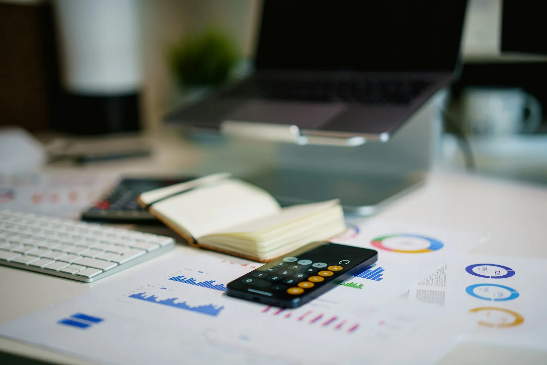 Printed financial charts, a calculator and a phone on an office desk