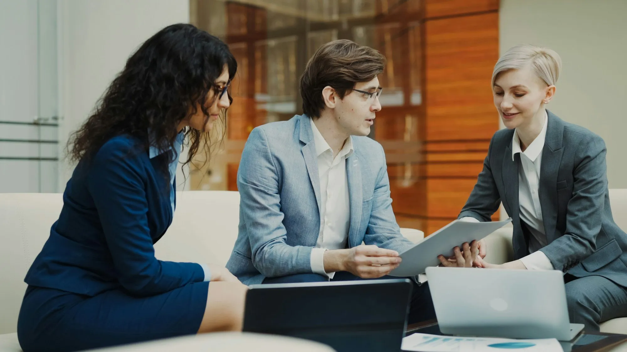 Three colleagues reviewing documents together on an office sofa